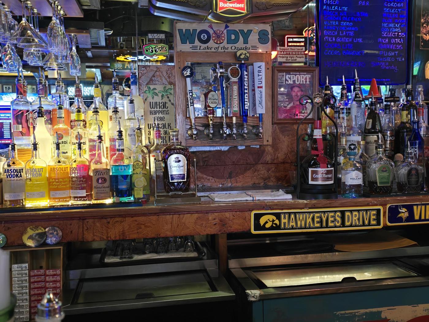 The back bar with the carved Woody's Lake of the Ozarks sign above the taps